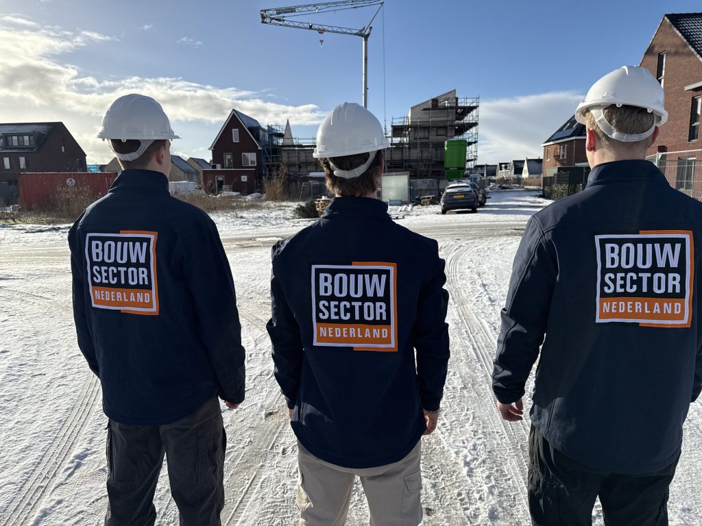 Drie vakmensen van Bouwsector Nederland met witte helm bij woningen in aanbouw